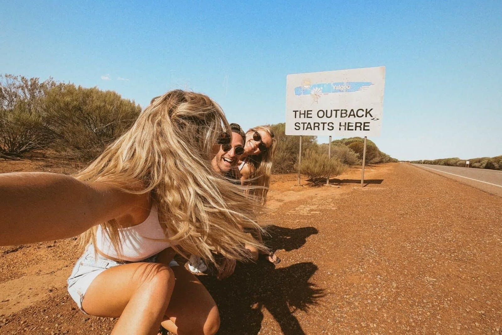Friends in front of an outback sign