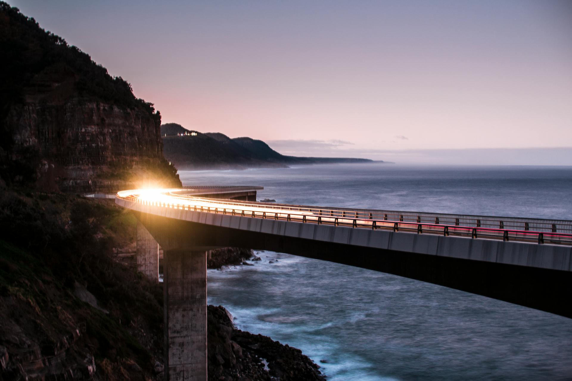 Car lights on the sea cliff bridge on the Australian Pacific Ocean coast.