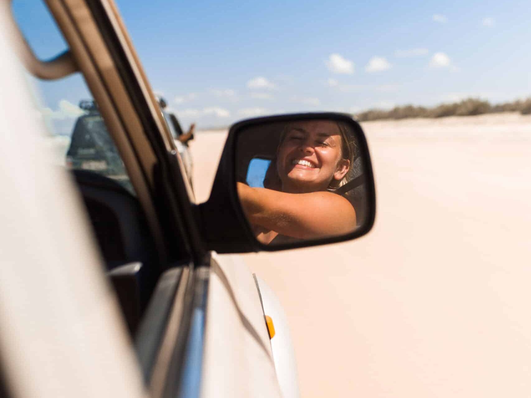 Woman smiling in the wing mirror while driving