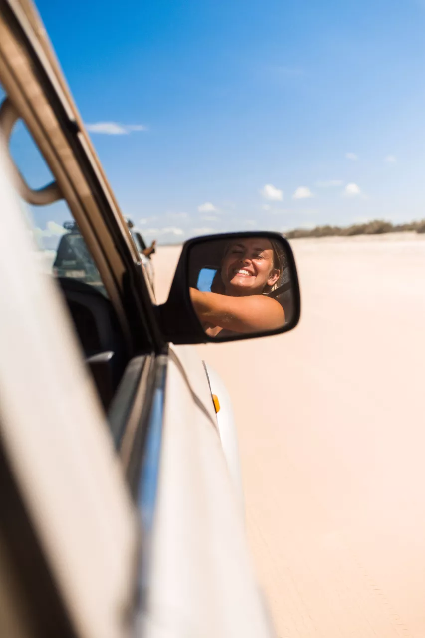 driving-smile Woman smiling in the wing mirror while driving