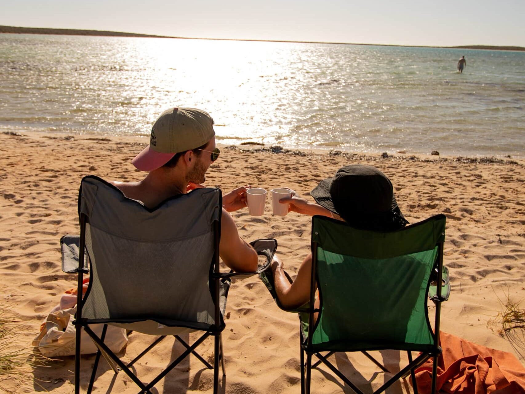 Two people sitting on camping chairs on the beach
