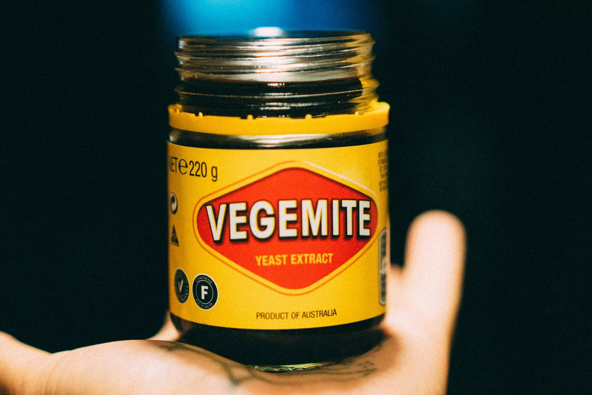 A jar of Vegemite on a person's hand