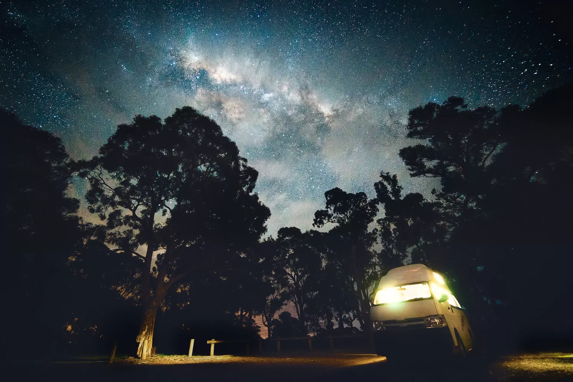 Campervan in a forest with a view of the Milky Way