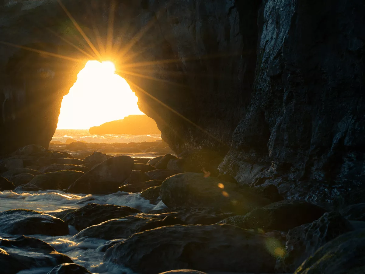 Cave Near Body of Water at Sunset
