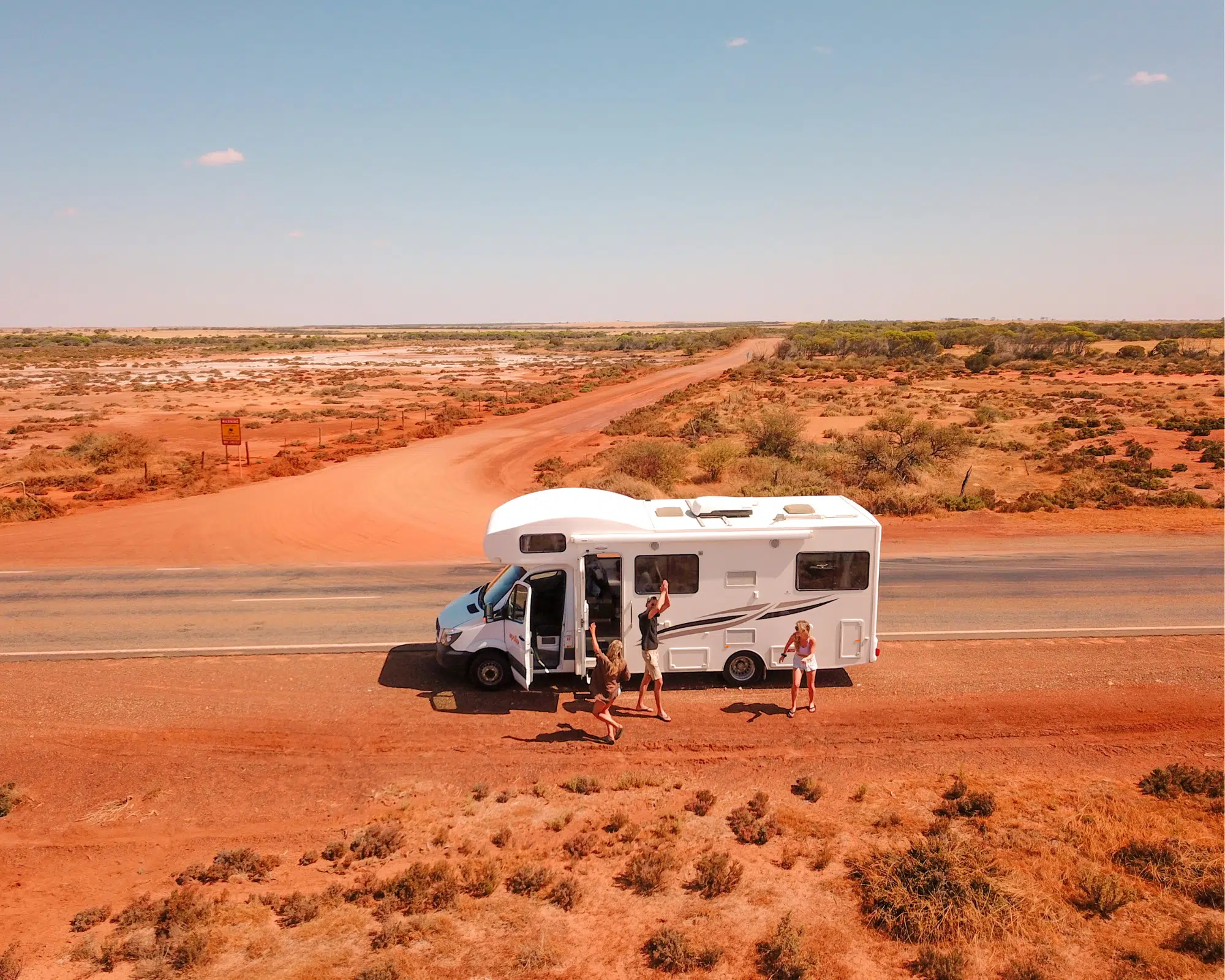 Friends-stepping-out-of-a-motorhome-in-the-middle-of-the-red-dirt-outback