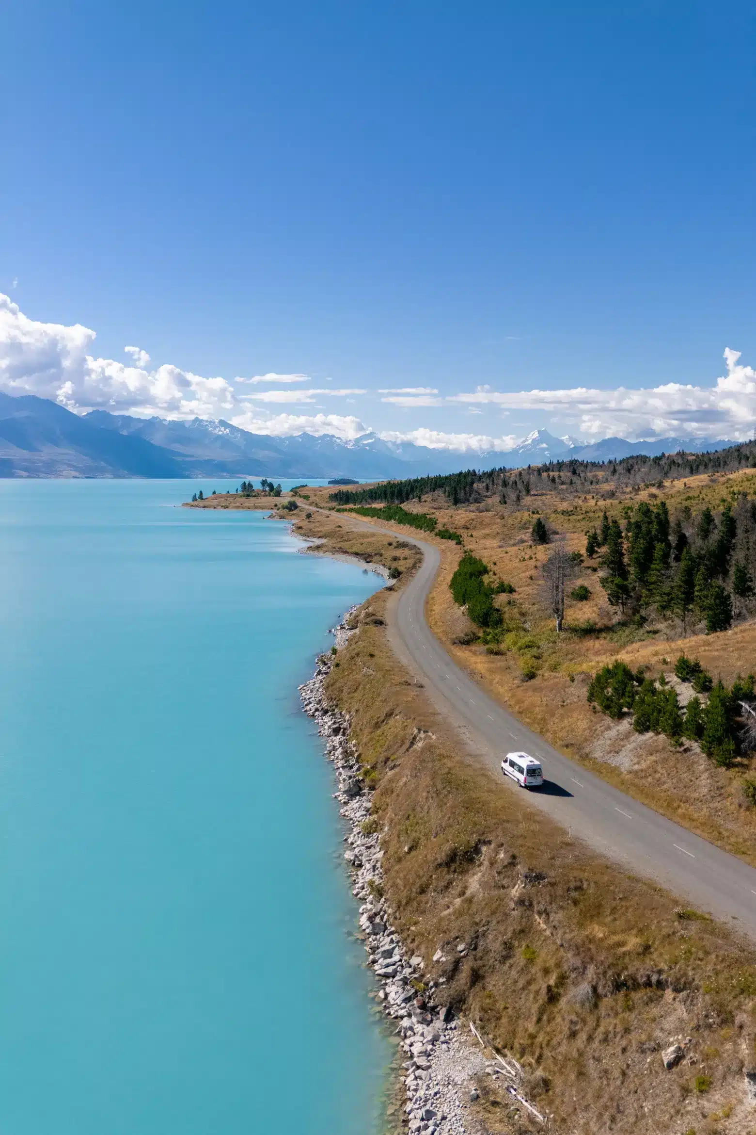 lake tekapo with campervan on the road next to it